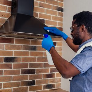 man cleaning residential cooktop vent hood